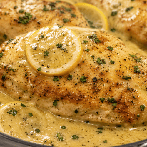 Close-up of creamy Chicken Limone with golden chicken breast, lemon slices, parsley, and rich lemon cream sauce.