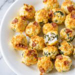 High protein egg bites with spinach and bacon on a white plate, perfect for low-carb meal prep breakfasts.