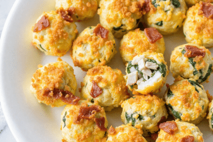 High protein egg bites with spinach and bacon on a white plate, perfect for low-carb meal prep breakfasts.