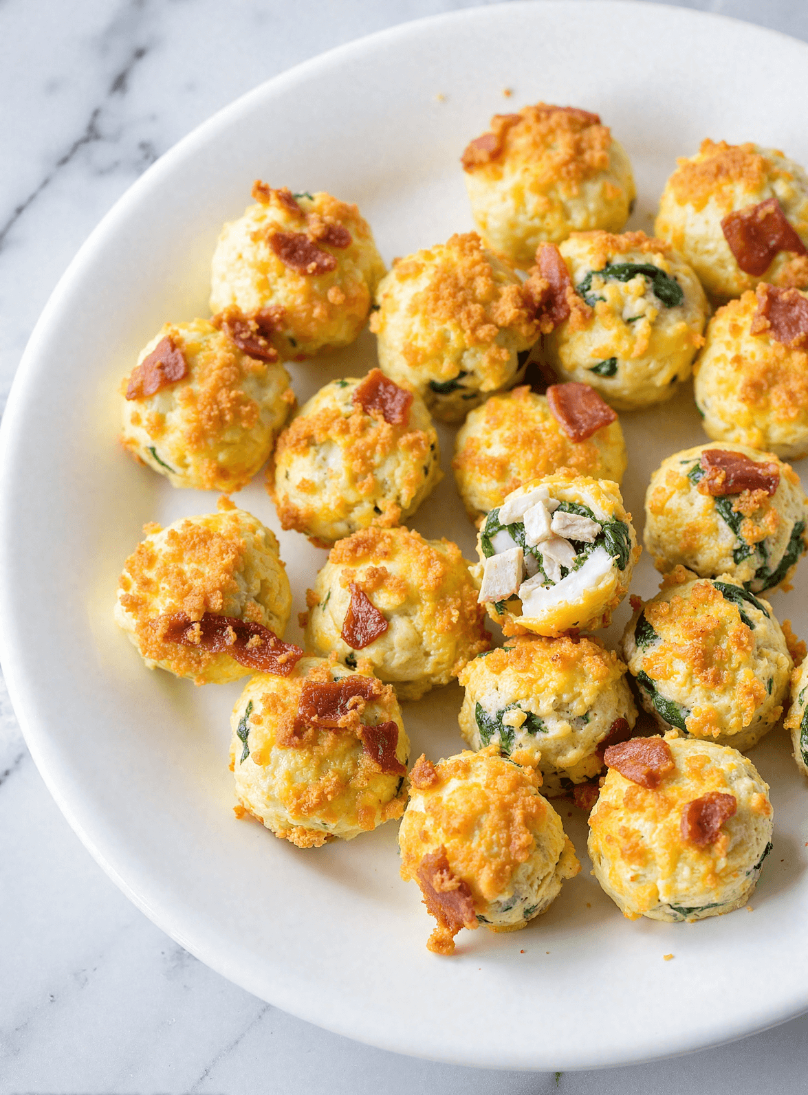 High protein egg bites with spinach and bacon on a white plate, perfect for low-carb meal prep breakfasts.