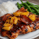 Grilled pineapple BBQ chicken topped with crispy beef bacon and caramelized pineapple chunks, served with rice and green beans for a quick sweet smoky dinner.