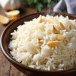 Fluffy garlic jasmine rice served in a bowl with golden fried garlic on top, styled on a rustic table – recipe by readyprepmeals
