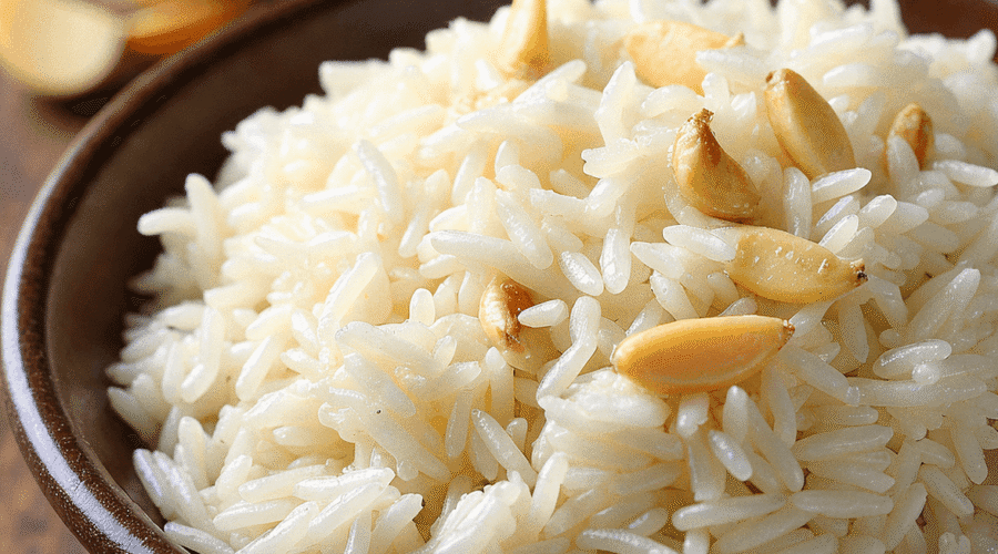 Fluffy garlic jasmine rice served in a bowl with golden fried garlic on top, styled on a rustic table – recipe by readyprepmeals