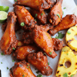Pile of grilled tropical BBQ chicken wings with crispy skin and caramelized pineapple-mango glaze, shot with Canon EOS 5D.