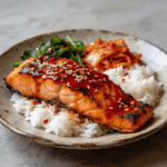 Korean gochujang salmon with rice, kimchi, and greens on a rustic plate