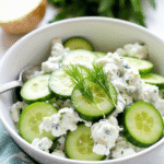 Chilled cucumber yogurt salad served in a white ceramic bowl, garnished with fresh dill and a drizzle of olive oil