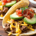 Three chorizo breakfast tacos filled with scrambled eggs, spicy sausage, melted cheese, and pico de gallo served on a rustic plate with lime wedges