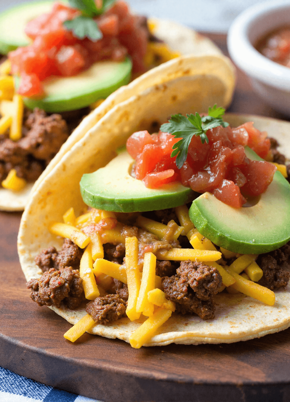 Three chorizo breakfast tacos filled with scrambled eggs, spicy sausage, melted cheese, and pico de gallo served on a rustic plate with lime wedges