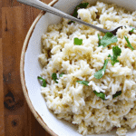Creamy garlic coconut rice served in a rustic bowl, garnished with fresh herbs