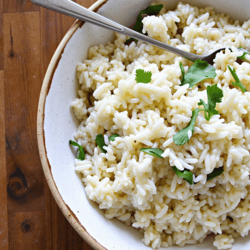 Creamy garlic coconut rice served in a rustic bowl, garnished with fresh herbs