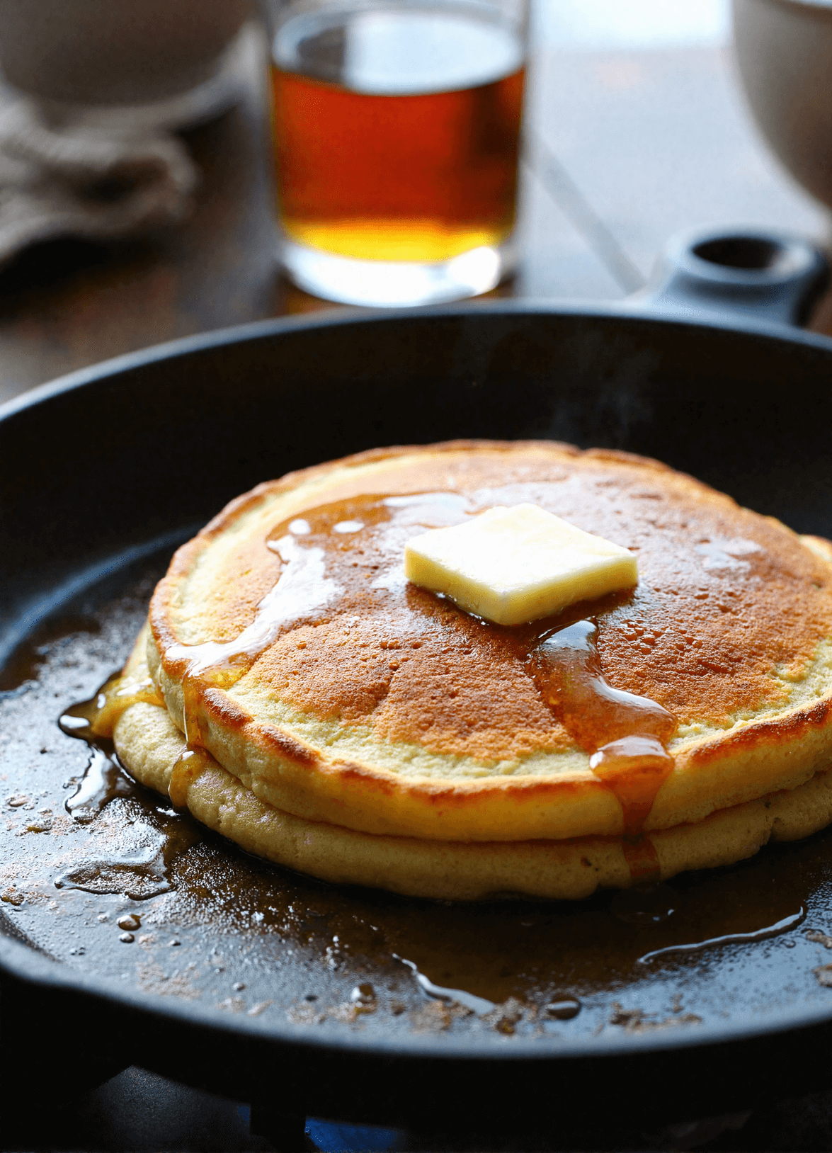 Fluffy maple bourbon pancakes in a skillet with melting butter and maple syrup drizzle, served hot for Father’s Day breakfast