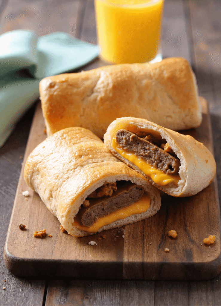 Stack of cheesy sausage, egg, and cheese breakfast roll-ups with gooey filling and golden crescent crust