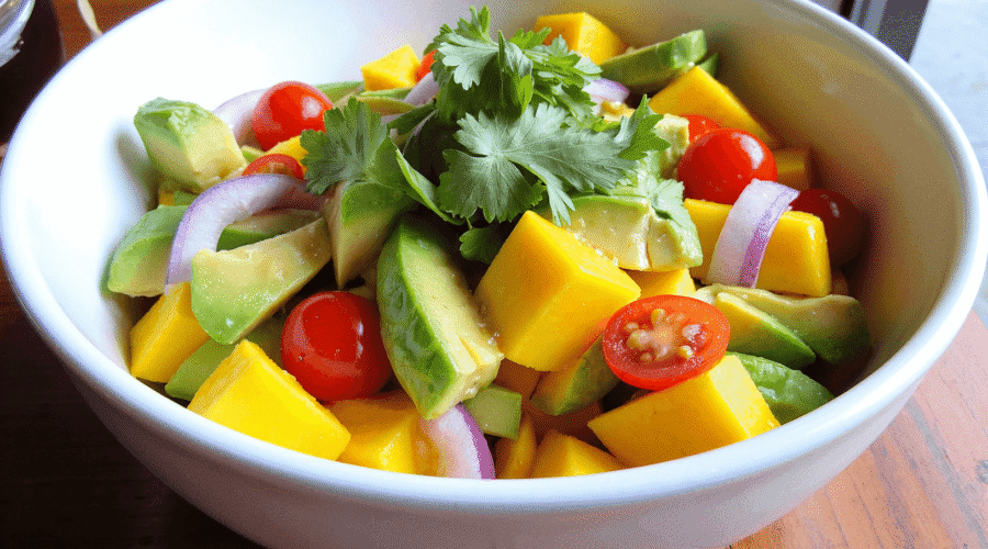 Tropical mango avocado salad with cherry tomatoes, red onions, and fresh herbs in a white ceramic bowl by Sam @readyprepmeals