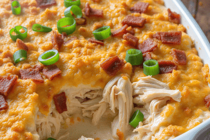 High-resolution photo of the Neiman Marcus chicken casserole featuring creamy shredded chicken, crispy bacon, cheddar cheese, green onions, and a golden Ritz cracker topping in a white baking dish.
