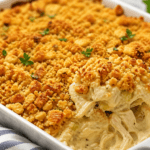 Creamy chicken casserole with crispy Ritz cracker topping being served from a baking dish