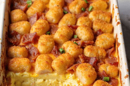 Golden brown bacon, egg, and tater tot casserole baked in a white dish with a crispy top and melted cheddar cheese.