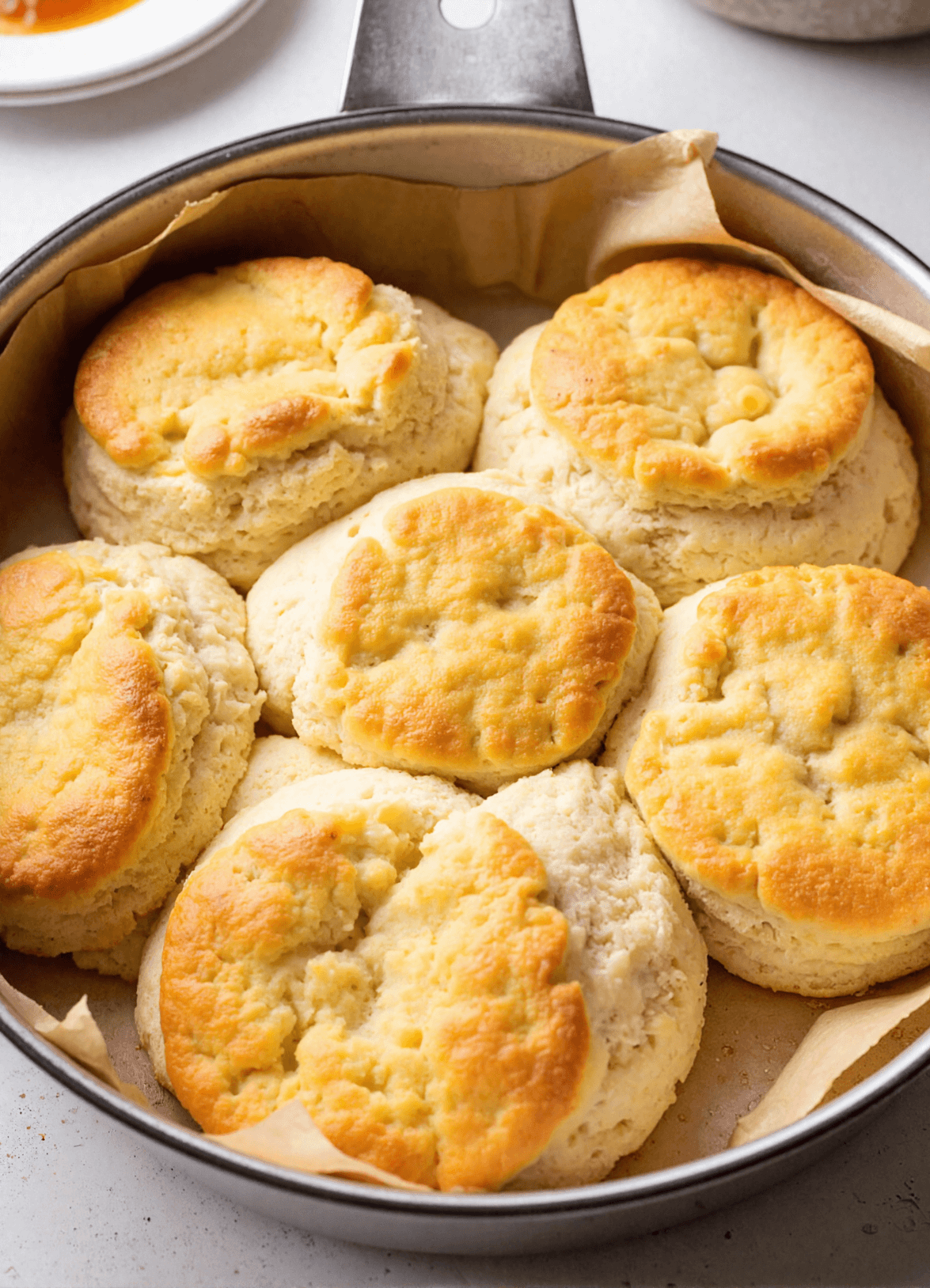 Freshly baked breakfast butter swim biscuits in a cast iron skillet lined with parchment paper, golden on top and fluffy inside.