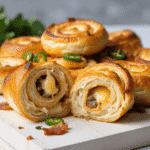 Close-up of sliced jalapeño popper pinwheels showing melted cheese and diced jalapeños in a flaky baked dough with crispy edges and sliced peppers.