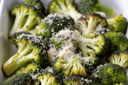 Roasted broccoli with parmesan cheese in a white ceramic baking dish on a rustic wooden table