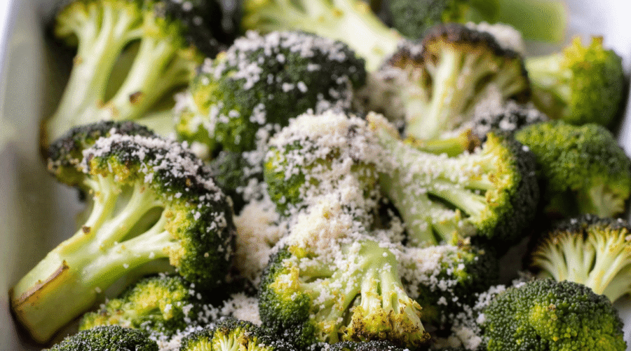 Roasted broccoli with parmesan cheese in a white ceramic baking dish on a rustic wooden table