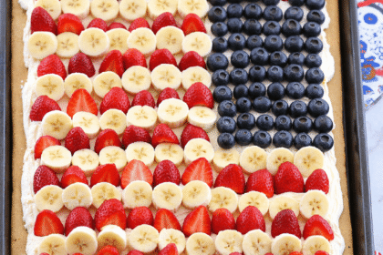 American Flag Fruit Pizza decorated with fresh strawberries, bananas, and blueberries on a sugar cookie crust for a festive 4th of July treat.