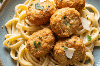 Plate of garlic butter chicken bites served atop creamy parmesan pasta with fresh herbs and shaved parmesan.