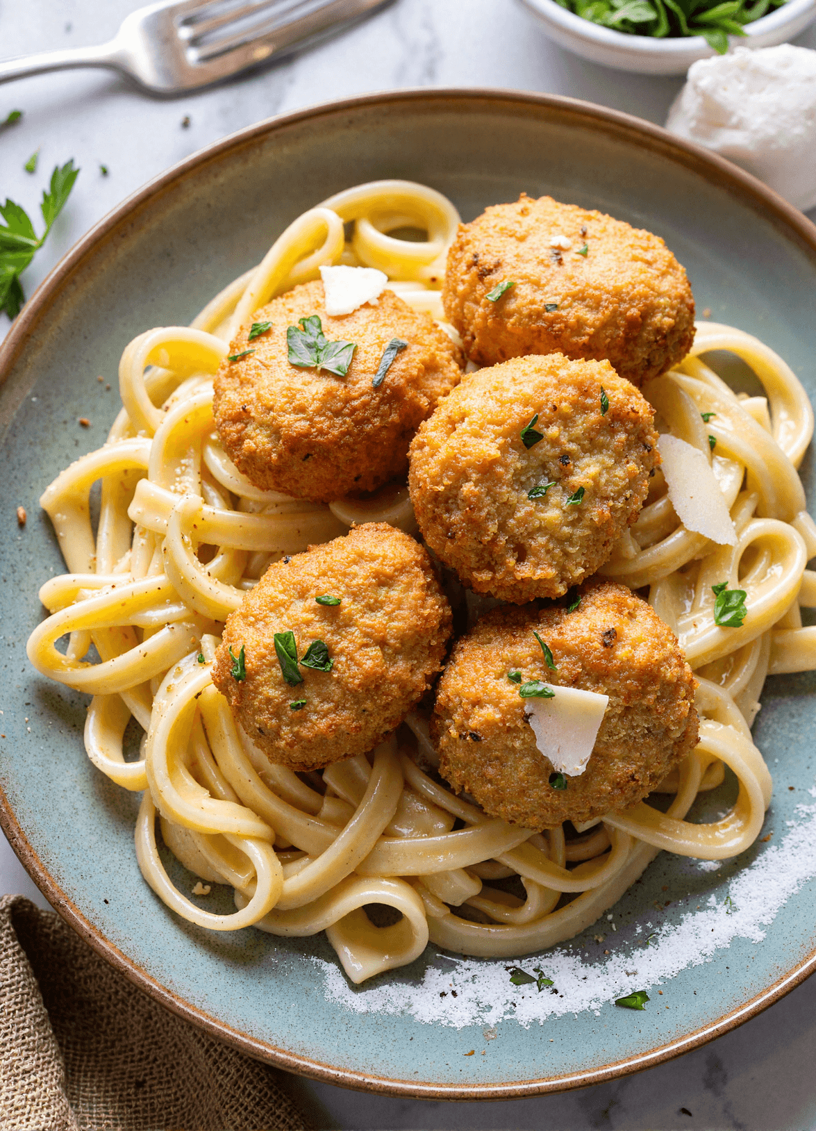 Plate of garlic butter chicken bites served atop creamy parmesan pasta with fresh herbs and shaved parmesan.