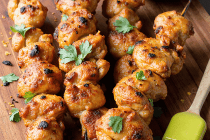 Grilled honey lime chicken skewers served on a wooden board with fresh lime wedges and cilantro