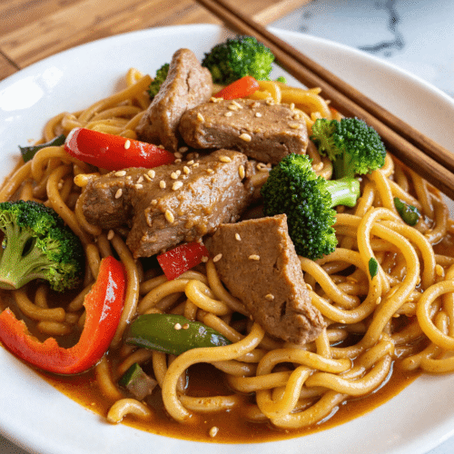Healthy Mongolian beef noodles in sauce with broccoli, red peppers, and sesame seeds.
