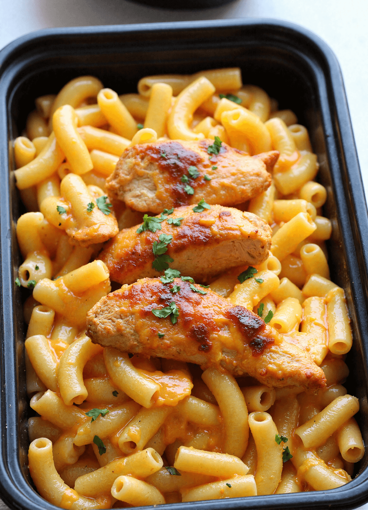 Meal prep container filled with high protein mac and cheese and grilled BBQ chicken breast