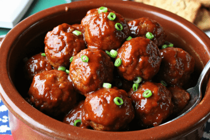Slow-cooked honey BBQ meatballs in a brown crockpot glazed with thick barbecue sauce and topped with sliced green onions.