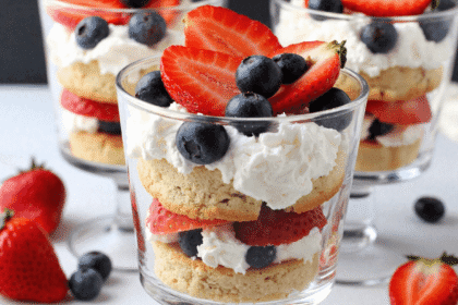 Mini berry trifles with strawberries, blueberries, whipped cream, and cake rounds served in small glass dessert cups.