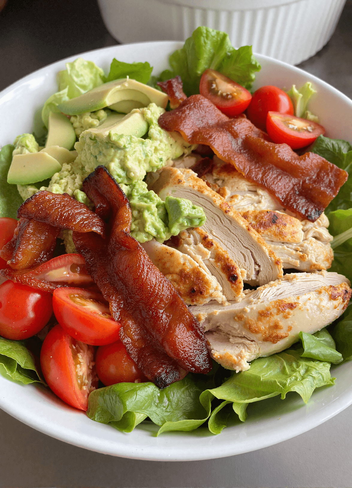 Keto BLT chicken salad with crispy bacon, grilled chicken, avocado, mashed avocado dressing, and cherry tomatoes