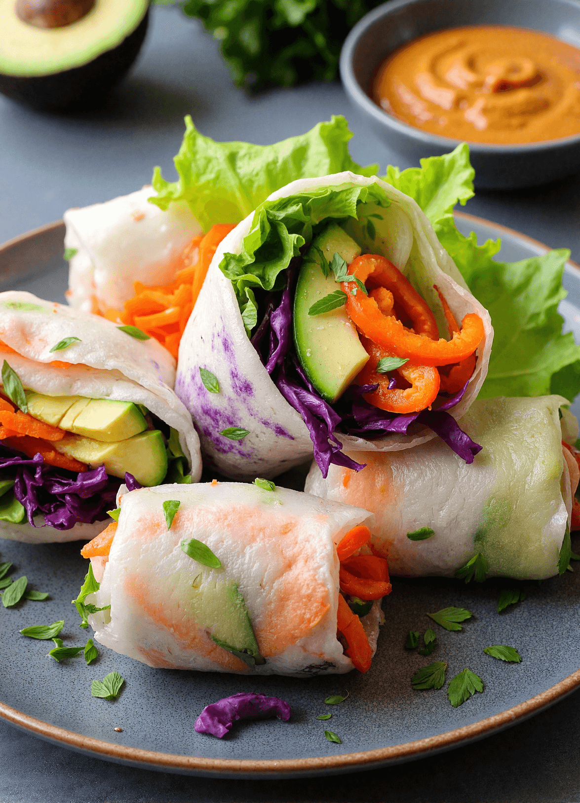rainbow veggie rice paper rolls with peanut sauce, filled with avocado, red bell pepper, purple cabbage, carrots, lettuce, served with creamy peanut dipping sauce