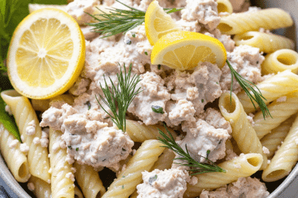 Bowl of tuna pasta salad with lemon and dill featuring rotini pasta, tuna chunks, fresh dill sprigs, and lemon wedges. High-protein pasta salad perfect for picnics.