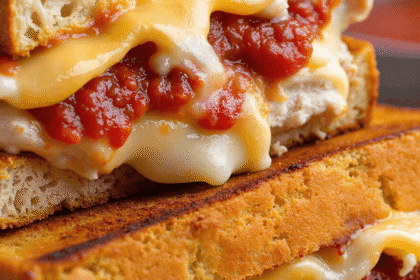 Close-up of Lazy Chicken Parmesan Grilled Cheese with gooey melted cheese and marinara sauce oozing between crispy golden bread