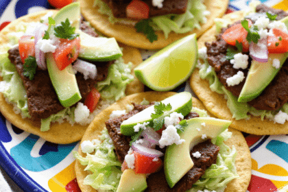 Authentic Mexican Tostadas de Carne Asada topped with grilled steak, avocado slices, shredded lettuce, and queso fresco on a vibrant plate.