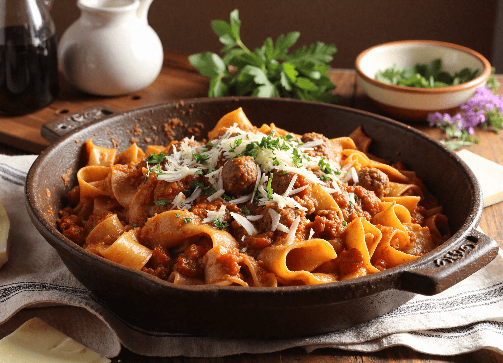 Pappardelle pasta with tomato-wine sauce and sausage in a rustic cast iron skillet.