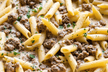 One-pot penne pasta with creamy ground beef sauce in a skillet, garnished with parsley.