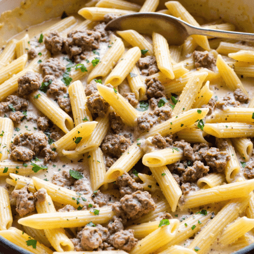 One-pot penne pasta with creamy ground beef sauce in a skillet, garnished with parsley.