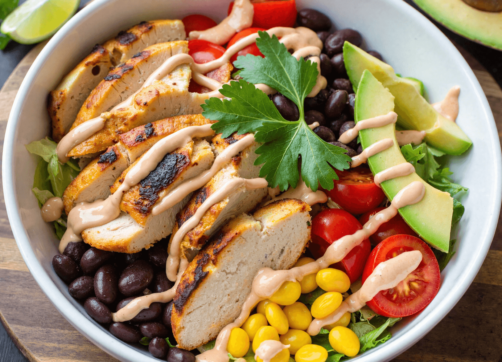 High-protein Southwest chicken salad bowl with grilled chicken, ground turkey, black beans, corn, tomatoes, and avocado.
