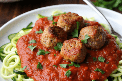 Baked turkey meatballs served over spiralized zucchini noodles and marinara sauce, garnished with parsley.