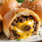 Close-up of baked cheeseburger bomb filled with gooey melted cheese and seasoned ground beef, topped with sesame seeds and parsley.