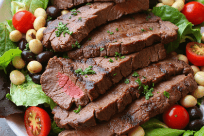 Grilled steak slices served over a vibrant green salad with black beans, cherry tomatoes, avocado slices, and red onion.