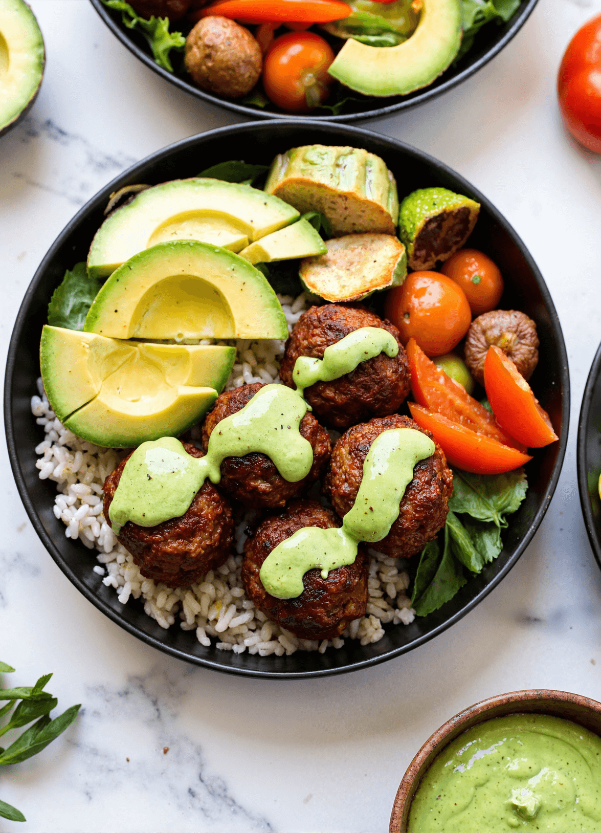 High-protein barbecue meatball bowl with avocado slices, rice, fresh vegetables, and creamy avocado goddess sauce.