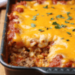 Baked cheese hamburger casserole with ground beef, pasta, marinara sauce, and melted cheddar topping in a black baking pan.
