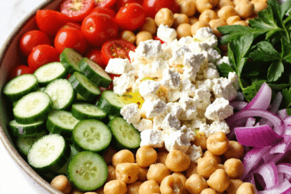 Chickpea cucumber feta salad in a rustic bowl with cherry tomatoes, parsley, onions, and olive oil.