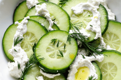 Bowl of cucumber slices with creamy Greek yogurt, fresh dill, and olive oil.