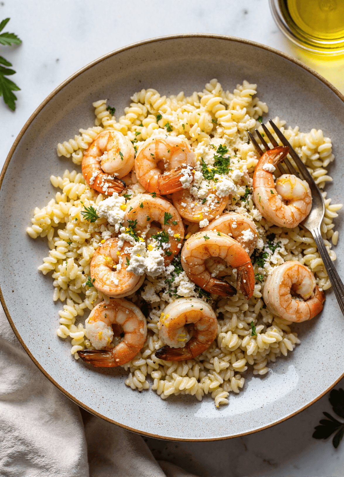 Plated lemon feta orzo shrimp garnished with fresh parsley, served in a rustic ceramic bowl.