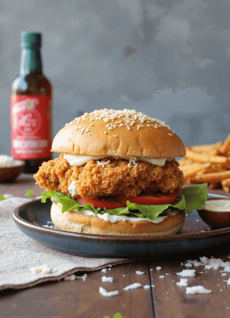 Crispy Chicken Caesar Sandwich stacked with lettuce, tomato, and creamy Caesar sauce on a sesame seed bun